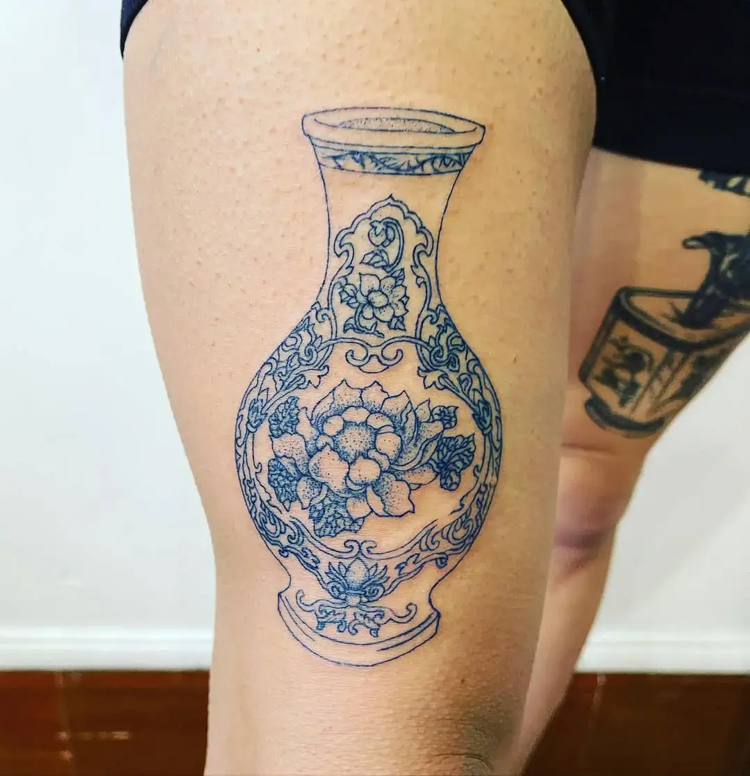 Photo d'un tatouage représentant un vase bleu sur une cuisse