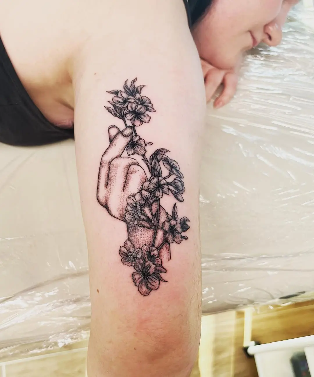 Tatouage sur un bras représentant une main tenant une fleur