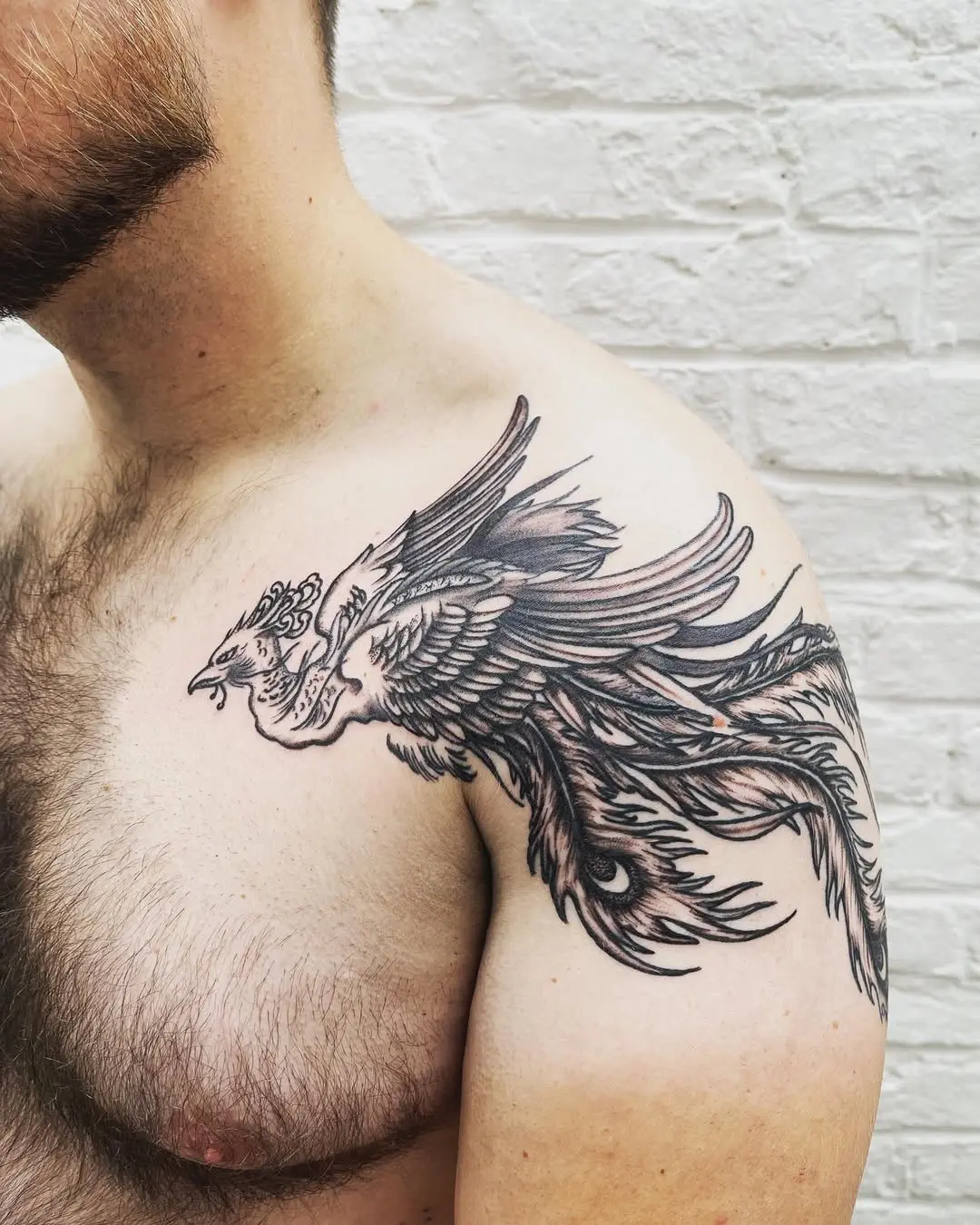 Photo d'une épaule tatouée. Le tatouage représente un phoenix