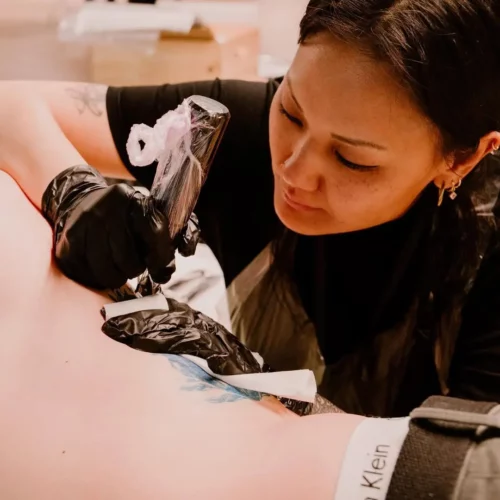 Photo de Juliette, tatoueuse chez YungTattooing, en train de tatouer