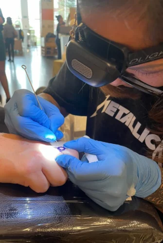 Photo de Juliette tatouant une main grâce à la technique du handpoke