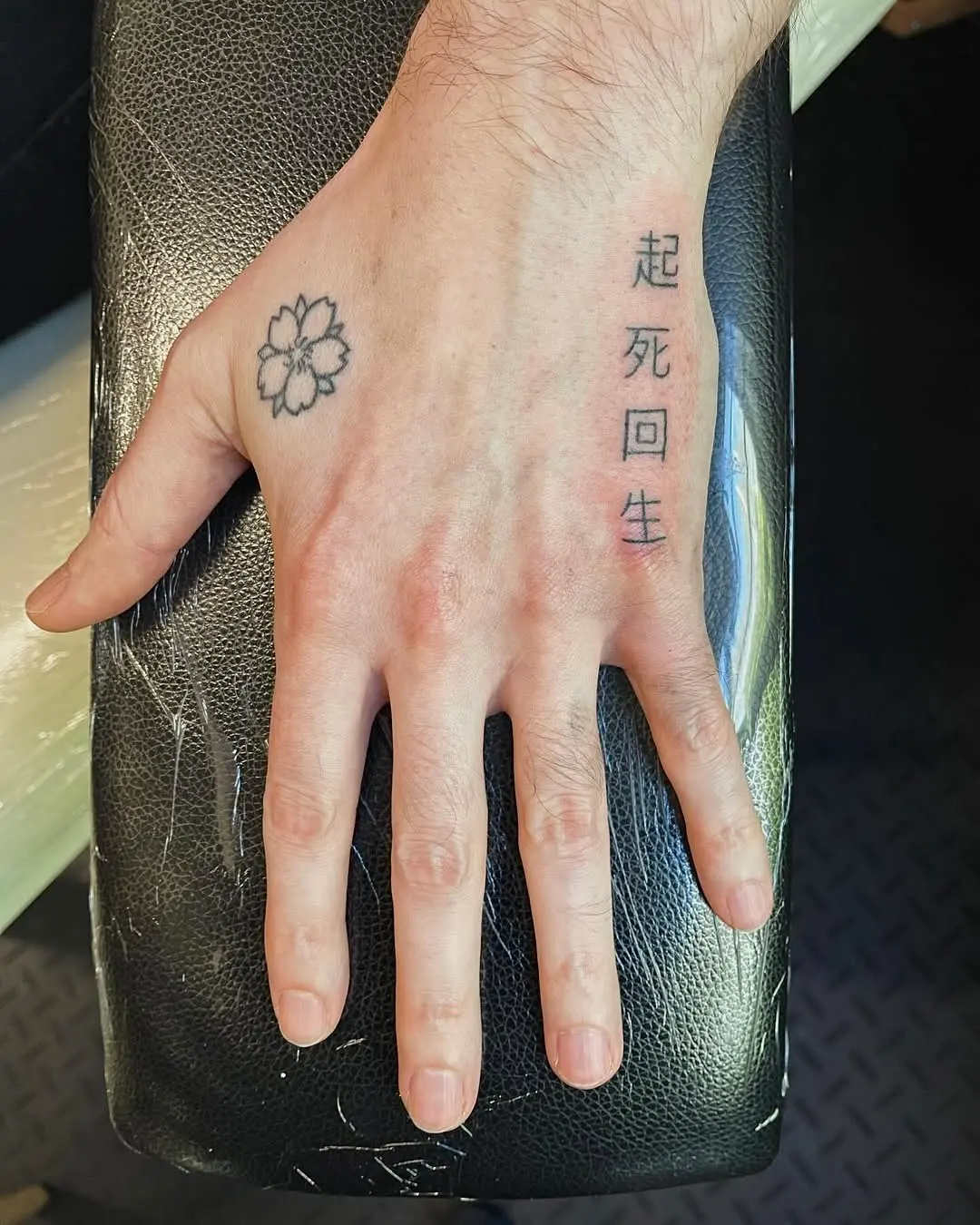 Photo d'une main tatouée avec une fleur de lotus et des idéogrammes japonais