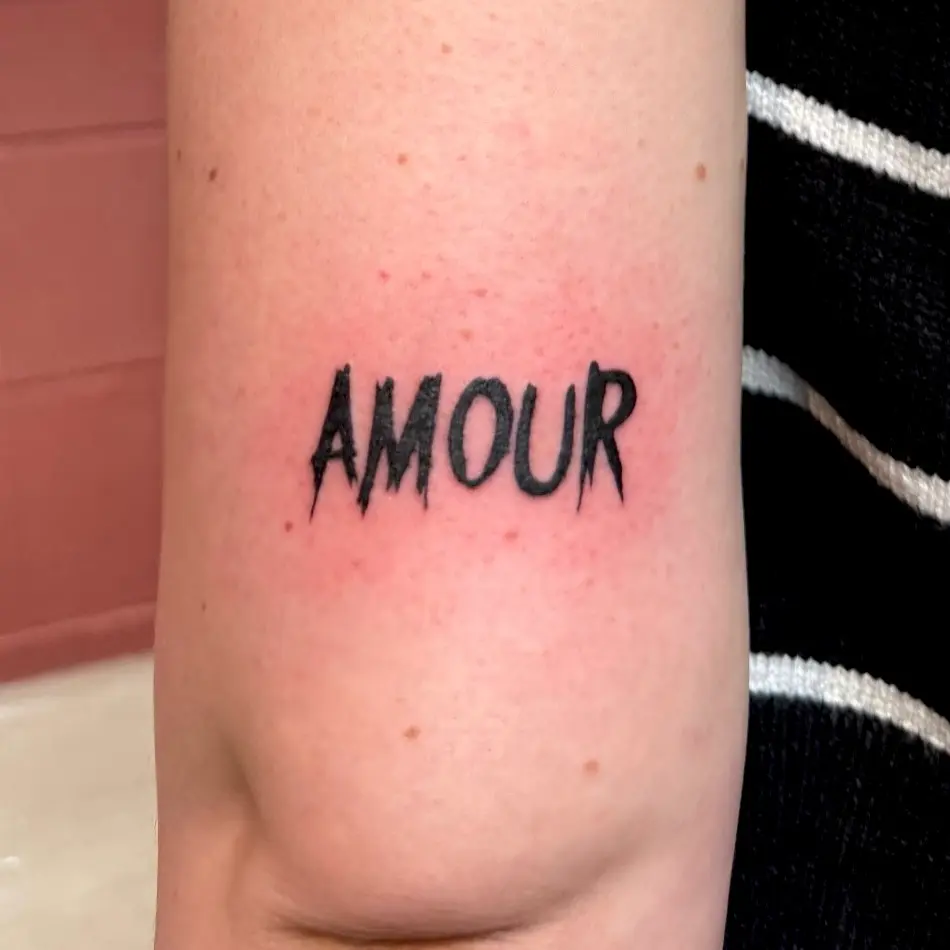 Photo d'un tatouage où il est écrit "AMOUR"